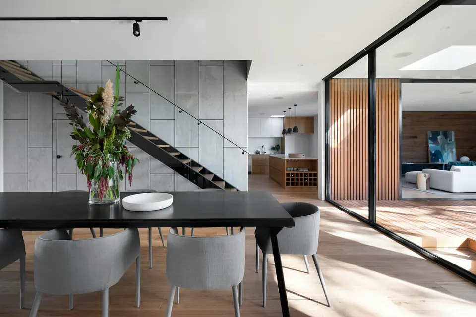 A dining room opening onto a sheltered timber terrace through glass doors